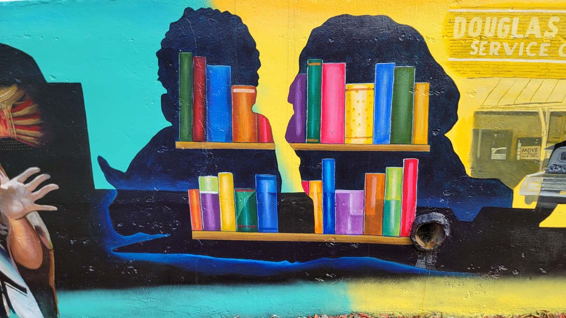 Mural painting of children's silhouettes, with books inside.